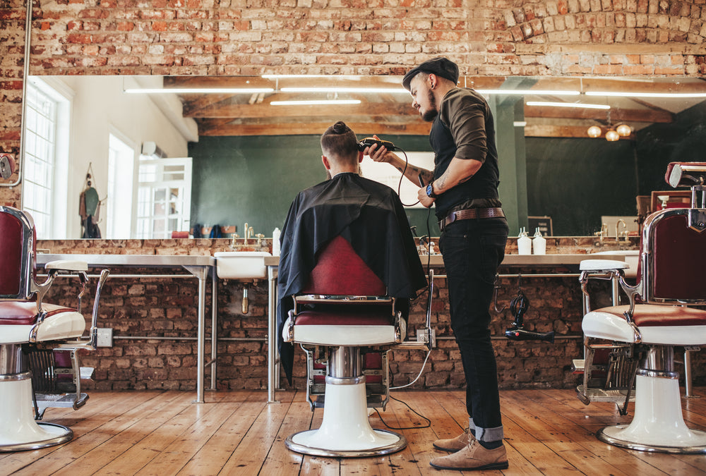 Rear view shot of hairdresser cutting hair of male client
