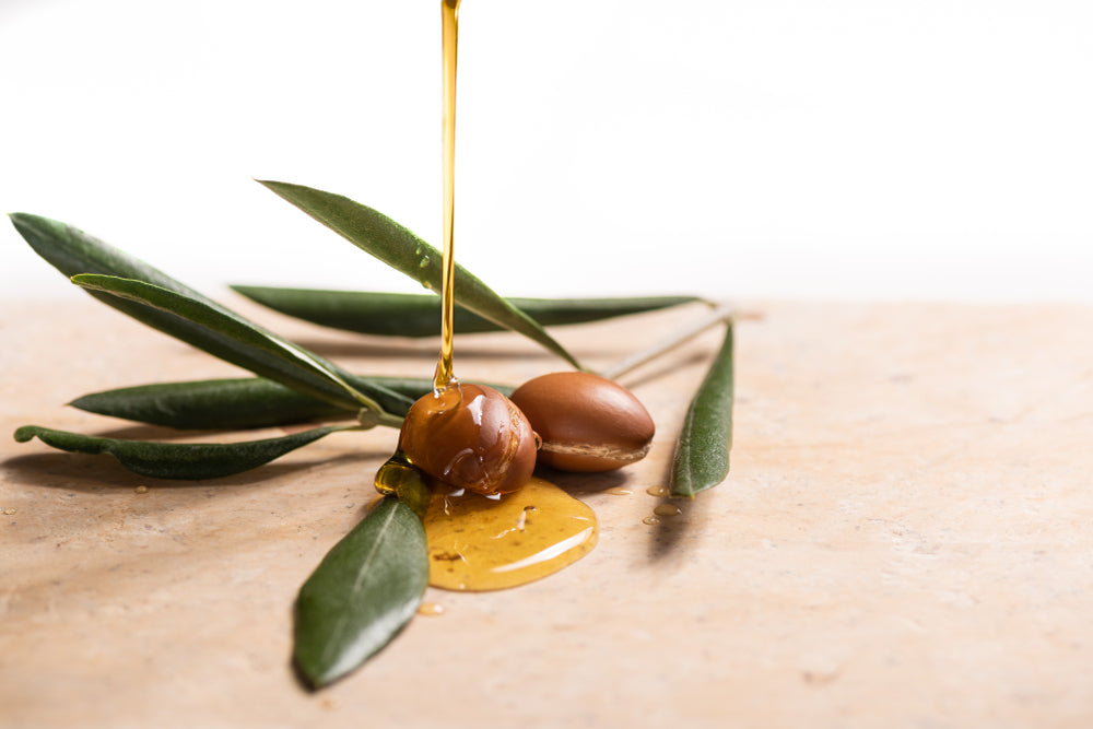 Argan oil, used for cosmetics, pouring over two argan seeds on a stone table