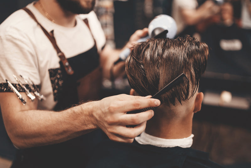 Close-up, master Barber does the hairstyle and styling with dryer